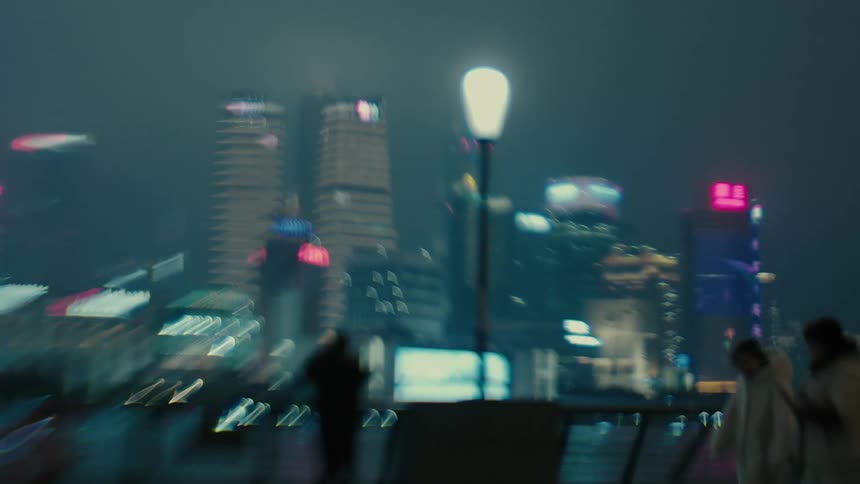 Parents walk with their children on the waterfront across the water from downtown skyscrapers at night