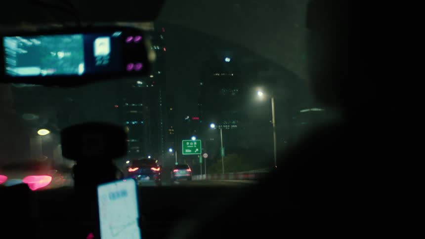 Inside view of the windshield of a car moving through the streets of a metropolis at night