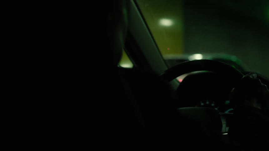 A man drives a car through city streets