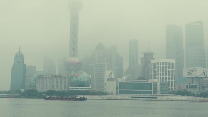 A ship passes by the fog covered city