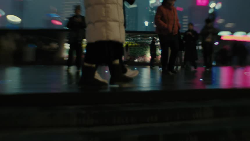 People walking in a square overlooking a shanghai metropolis illuminated at night
