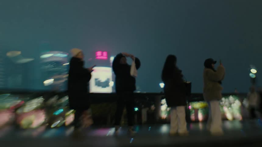 People in a city square at night with skyscrapers around
