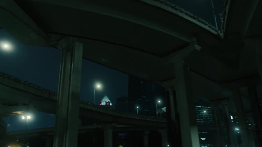 A nighttime cityscape with street lights under an overpass
