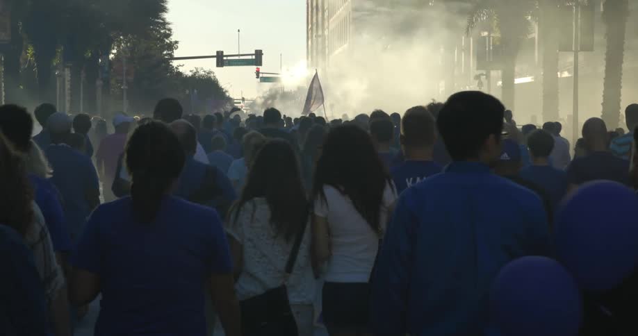 Large group of people walking down a misty street