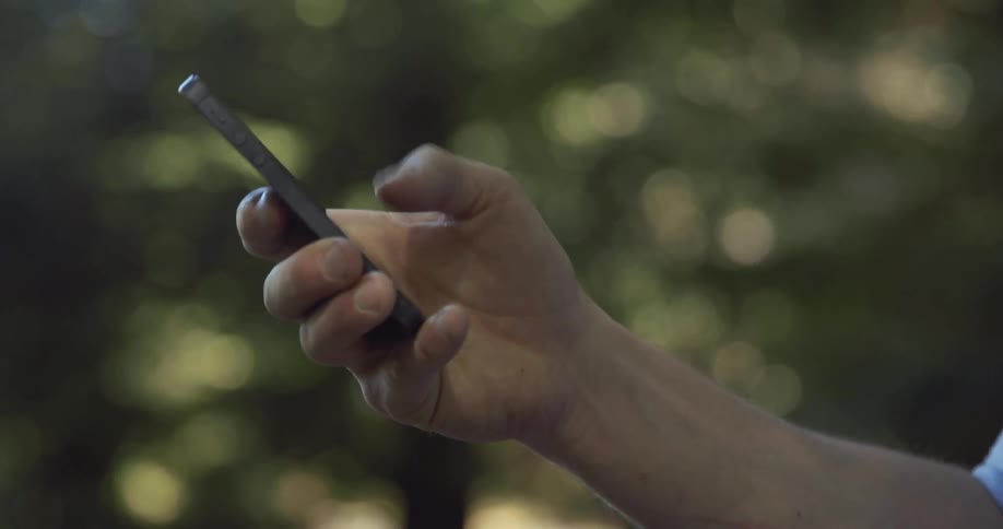 A person holds a cell phone and presses buttons on the touch screen