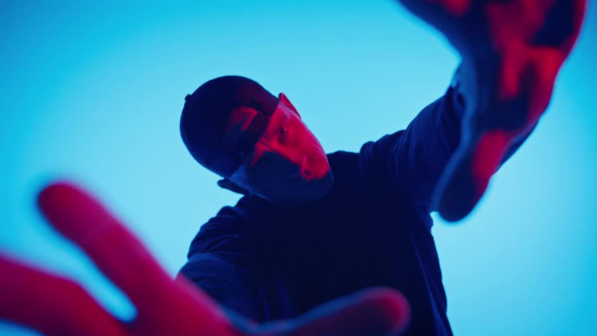 A man twists his body with arms outstretched in front of a blue screen