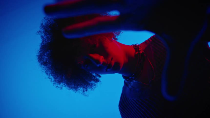 Face of a young model with his palm in a studio environment with electric blue lighting