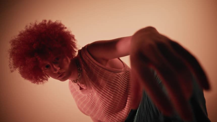 Curlyhaired man modeling while squatting in a studio with warm lighting