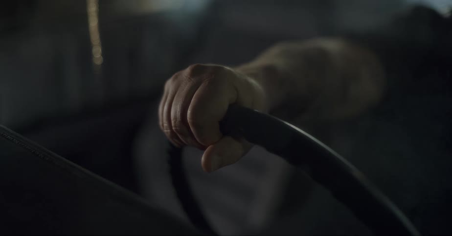 Closeup of a mans hand holding the steering wheel as the cars internal smoke begins to expand