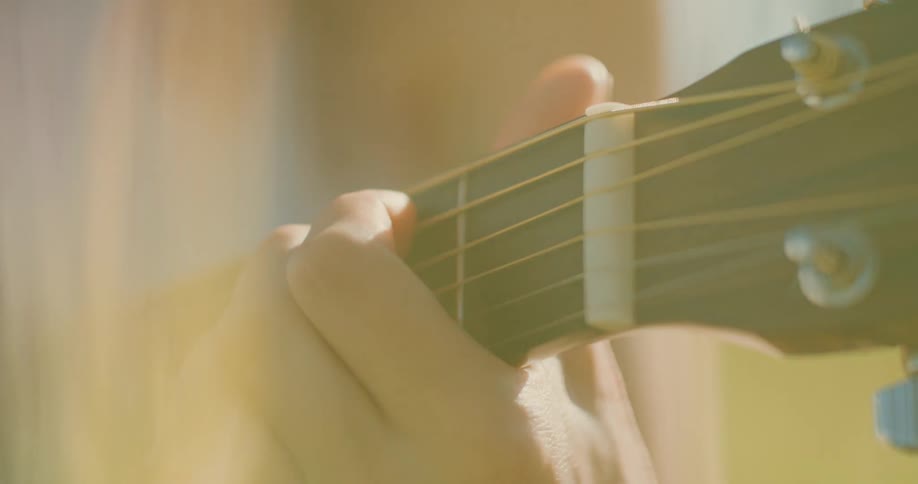 Musician moves their fingers on the fretboard as they play the guitar