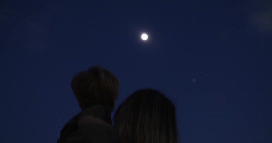 A mother and child points at a solar eclipse