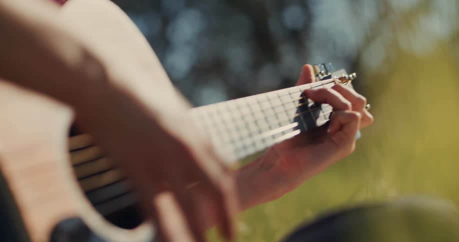 A man is playing the guitar on a sunny day