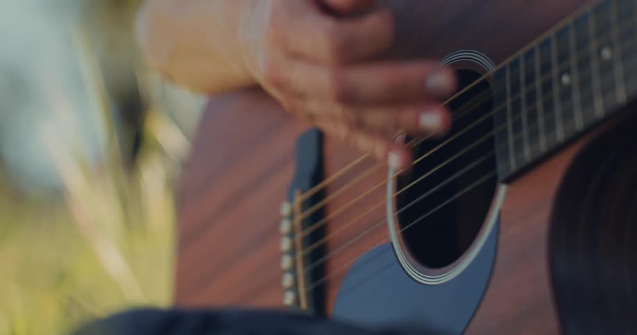 A man strums a guitar outdoors