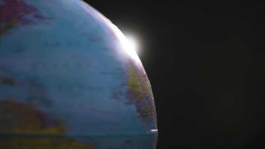 Sunlight shines over a small spinning globe