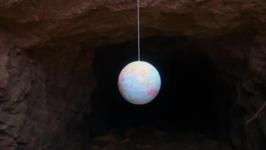 Orbiting earth globe hanging on a wire in a natural cave