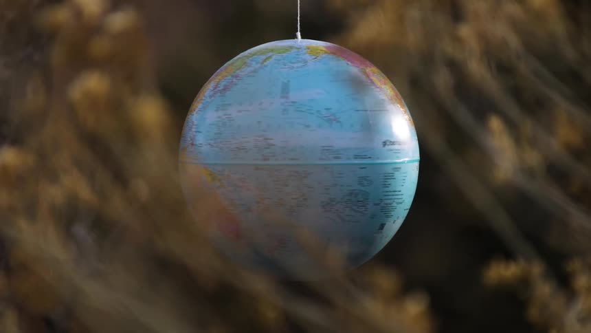 Earth globe rotating and being held by a thread in a natural environment