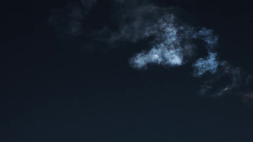 White rocket smoke swirls fading against a dark background