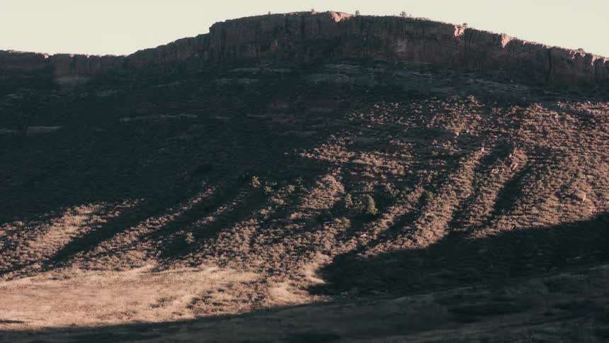 Time lapse of sunlight lighting the slopes of a mountain in the desert