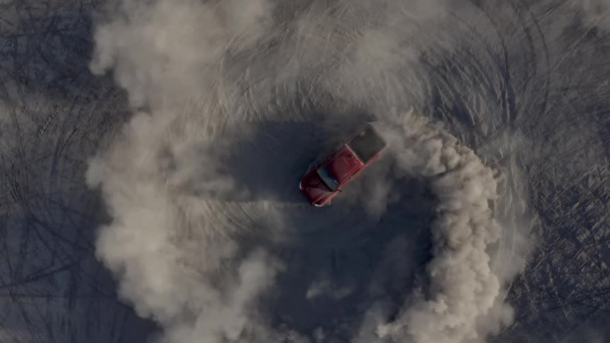 Truck leaves a trail of smoke as it spins around in a circle doing donuts in the desert