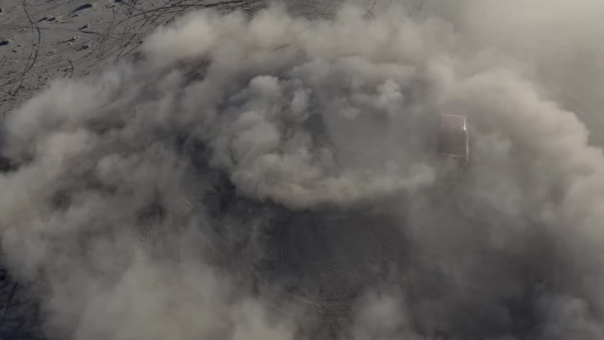 A pickup truck rises rings of dust from the ground