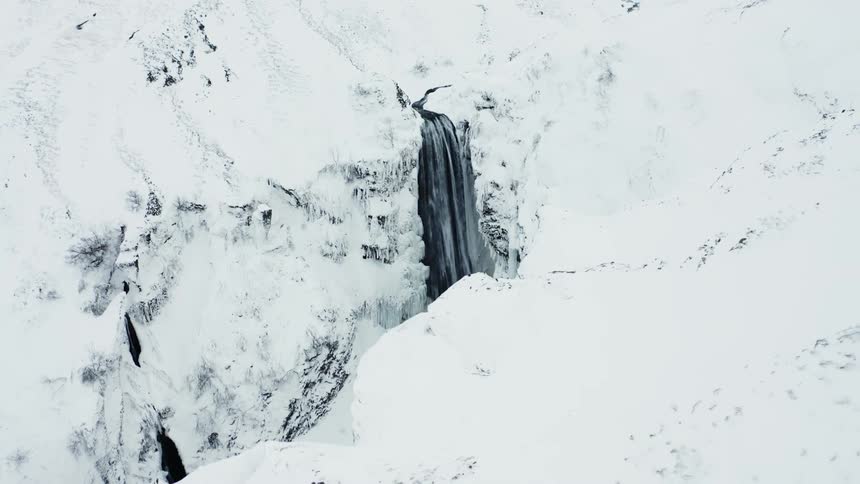 Aerial scenery of a waterfall in snowcovered mountains