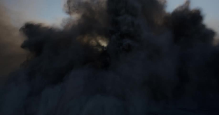 Truck drives quickly through the desert creating dust that obscures the nearby rock formation