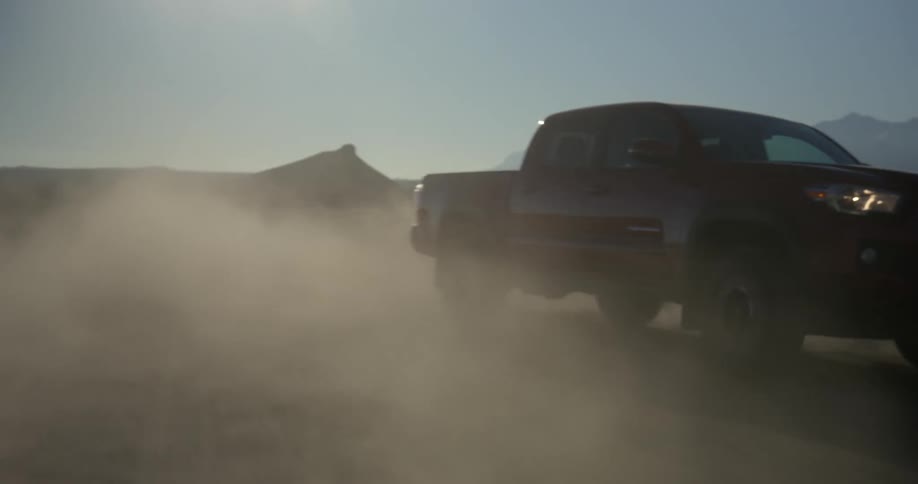 Wind blows the sand as a truck travels across the desert
