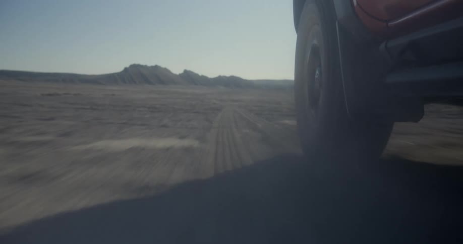 Close up of a car driving at full speed in middle of nowhere towards the mountain