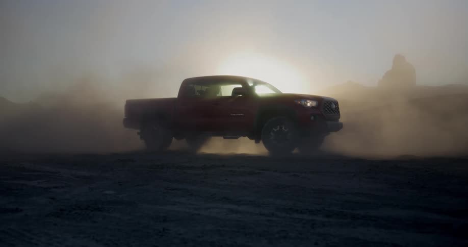 Pick up truck picks up dust in front of sun flare outdoors