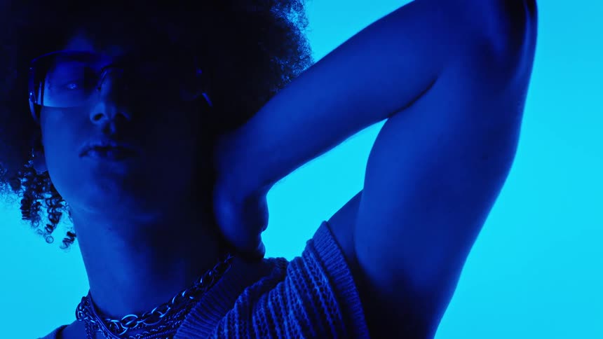 Person with curly afro models under blue light