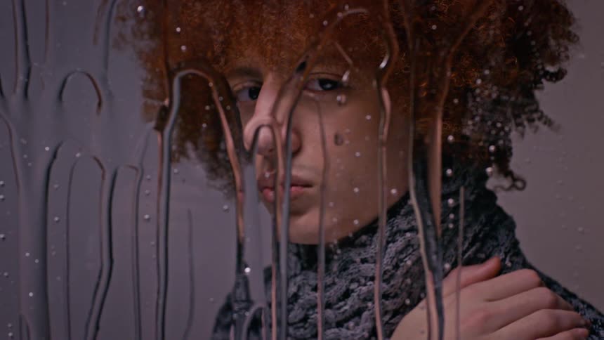 Portrait of a model man in front of a mirror with transparent liquid dripping down