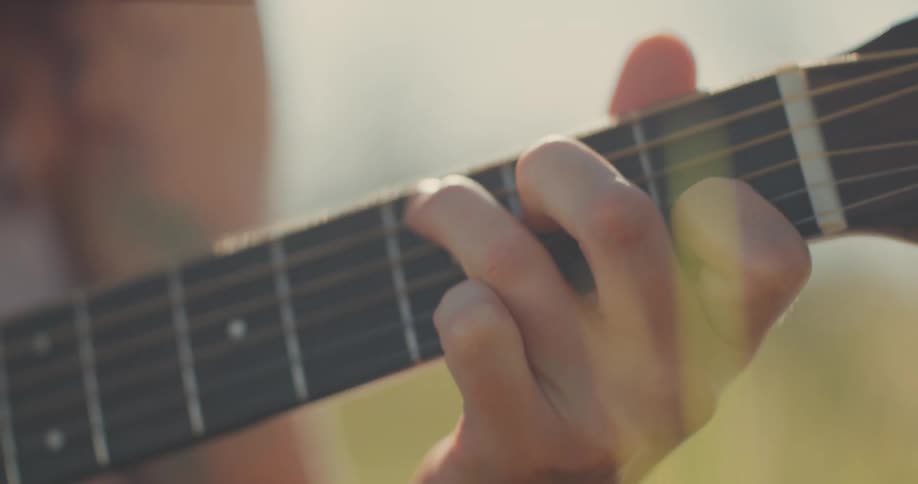 Womans hand in a field playing the guitar