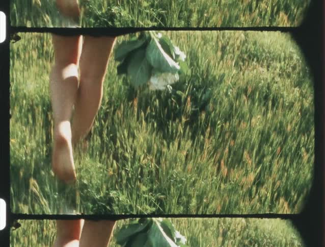 A woman walking on the grass barefoot caught on vintage film