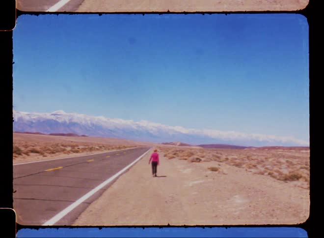 A person is walking by the highway in the desert