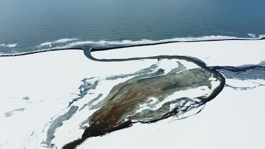 Aerial panorama of a snowcovered seaside terrain with a river channel