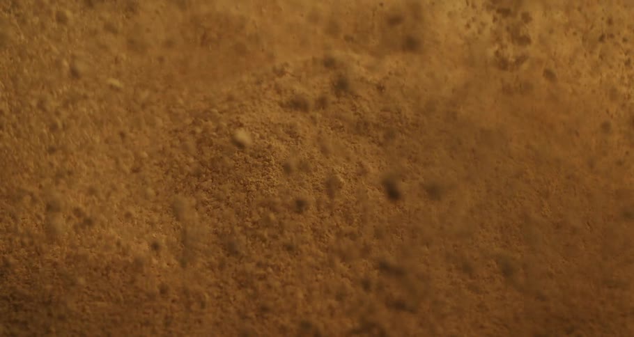 Closeup on a sand floor exploding and falling in slow motion