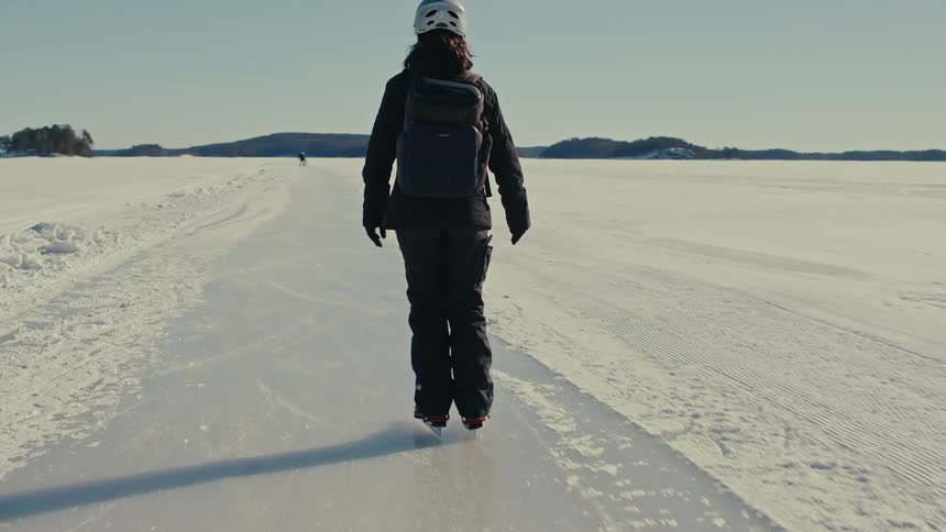View of a woman from behind skating on open ice in a natural environment