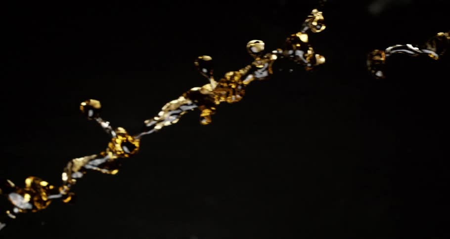 Golden liquid with black thrown in slow motion on a black background