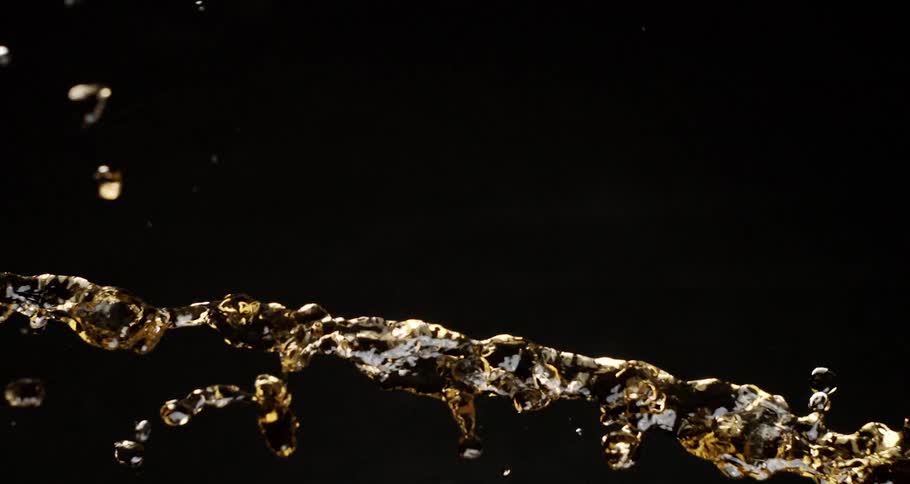 Splash of golden fluid flows through the dark air