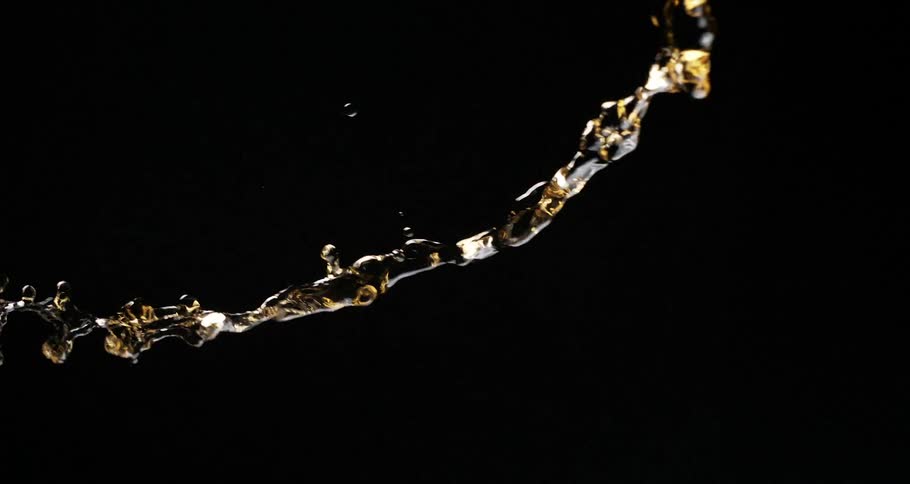 Liquid splashing into the air and falling in slow motion on a black background