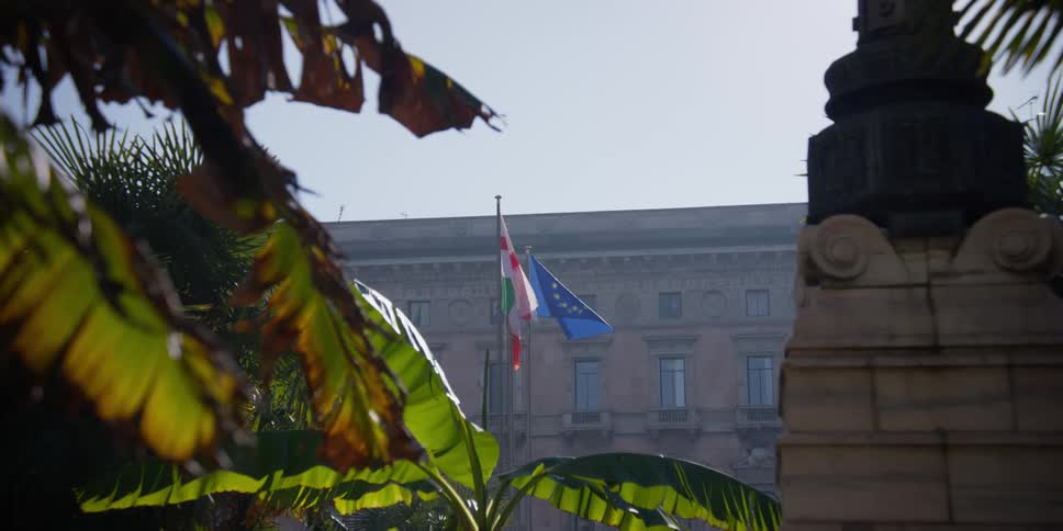 Multiple flags flap in wind near the Palazzo Carminati in Milan on a sunny day