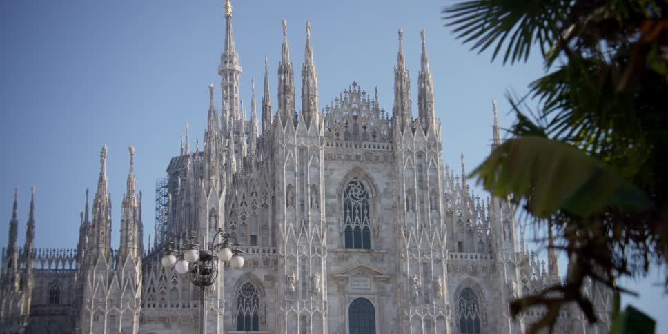 Facade of Cathedral Duomo di Milano in Milan, Italy on a cloudless blue sky day