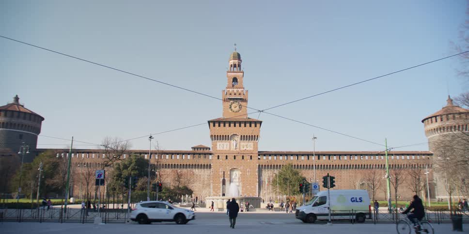 Traffic and pedestrians move in front of the Torre del Filarete of Sforza Castle in Milan, Italy