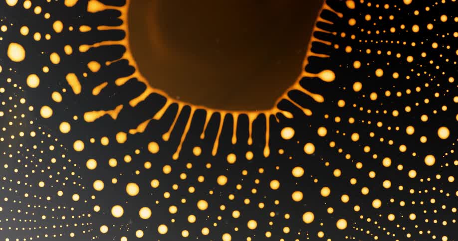 Abstract pattern of a liquid succumbing and forming small golden droplets