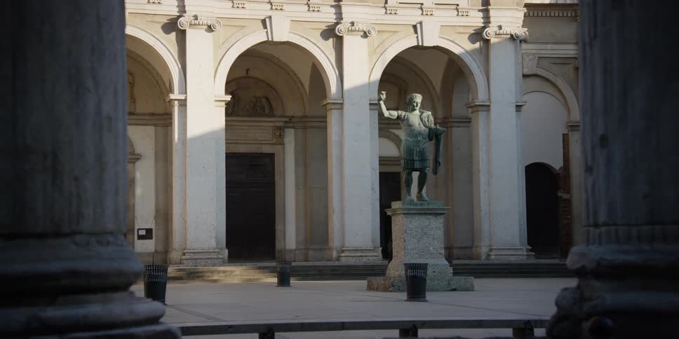 A person walks near a statue of roman emperor Constantine in front of San Lorenzo Maggiore Basilica