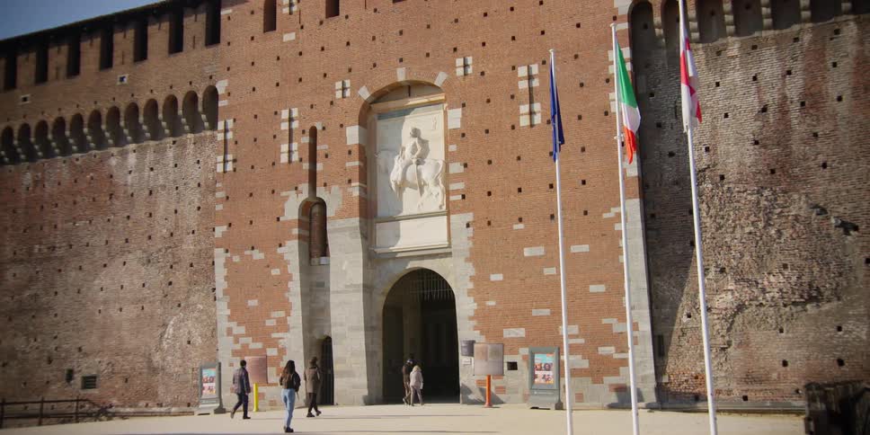 Tourists walked through arched entry of the Torre del Filarete of Sforza Castle in Milan, Italy