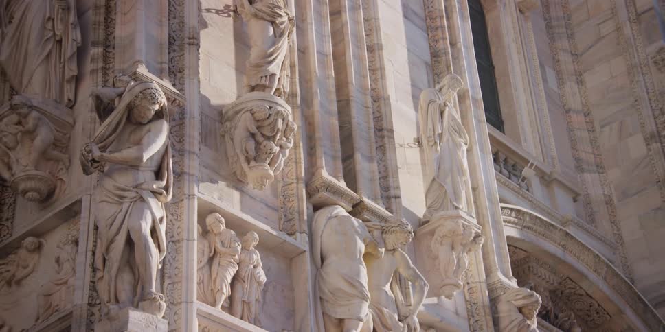 Facade of the Cathedral Duomo di Milano in Milan, Italy with monuments and sculptures reflected by sunlight