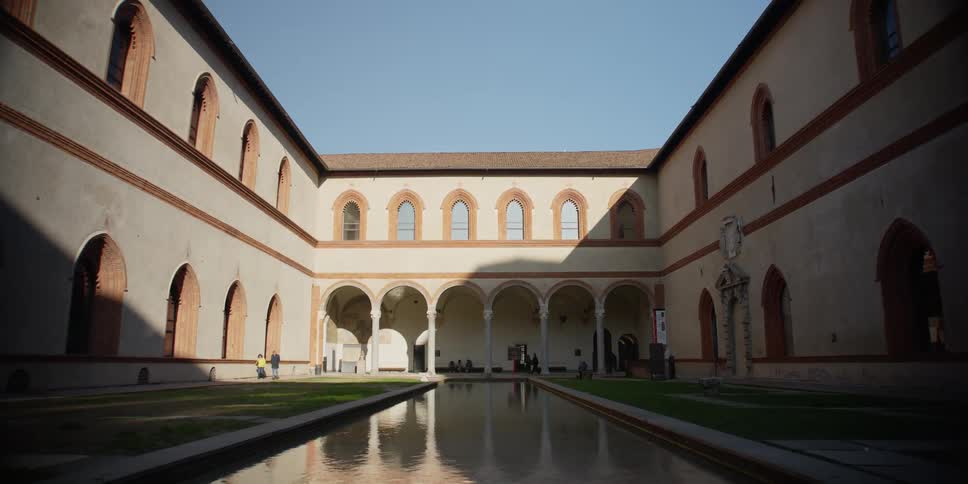 People walk around the ducal courtyard and pool in the Castello Sforzesco, Milan, Italy