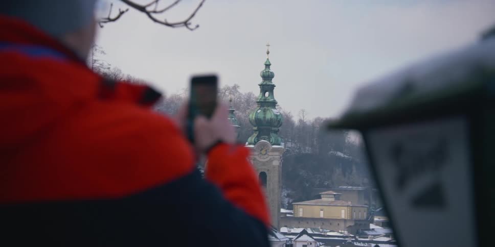 Man holding a smartphone and taking photos of Salzburg cathedrals in Austria