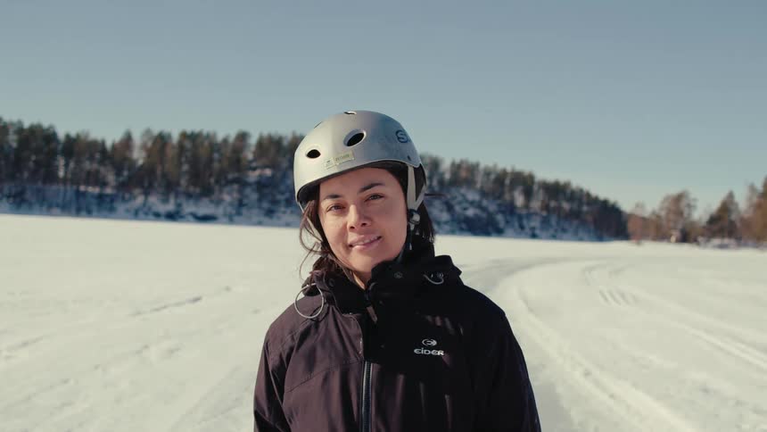 A woman wearing a helmet is smiling in the snow